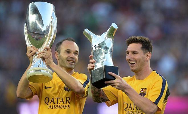 Lionel Messi lifts up his UEFA Best Player in Europe Award past Barcelona's midfielder Andres Iniesta holding the UEFA Supercup before the game.