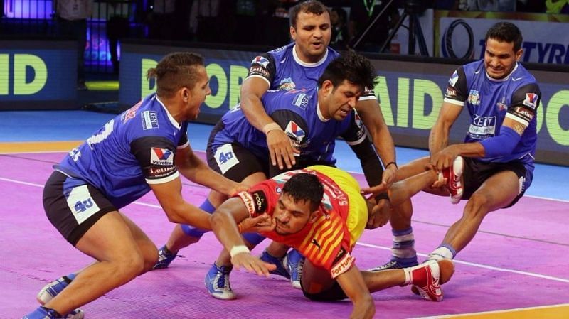 Surender Nada (right) attempts an ankle hold on a Gujarat raider