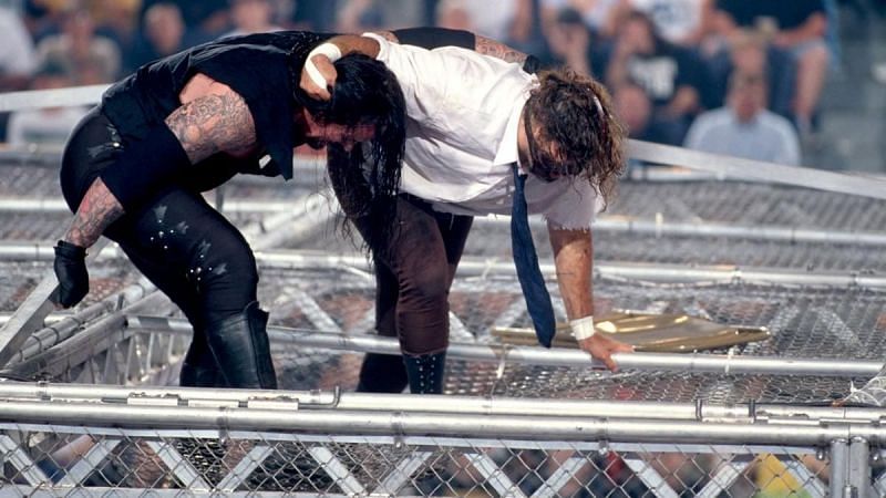 Undertaker and Mamkind battling back and forth along the top of the cage.