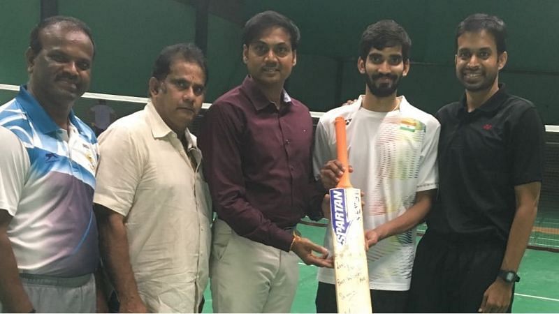 Srikanth Kidambi poses with his autographed bat alongside MSK Prasad and coach Pullela Gopichand