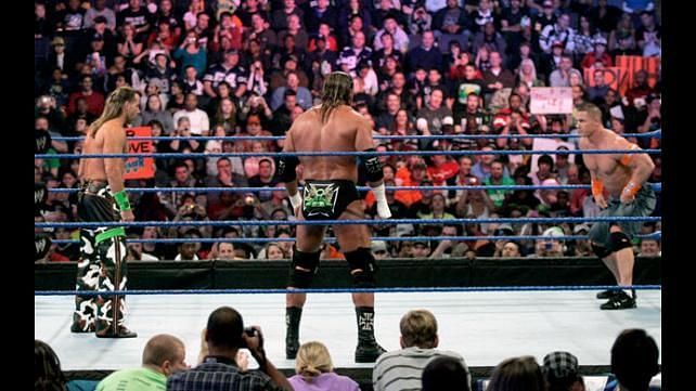 Shawn Michaels, Triple H, and John Cena squaring-off in a WWE ring 