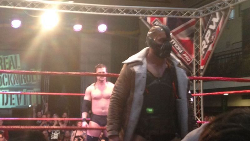 Devitt making his Bane entrance with Adam Cole at the back