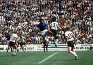 1970 World Cup Semi-Final, Mexico City, Mexico 17th June, 1970. Italy 4 v West Germany 3. West German player Gerd Muller jumps for the ball with an Italian defender as teammates Uwe Seeler (9) and Jurgen Grabowski (20) look on during the two teams' semi-