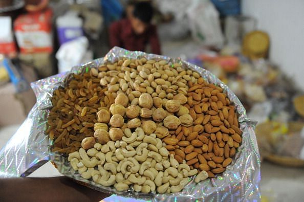 Indian workers weigh packets of dry frui
