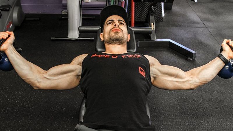 Man flexing his muscles while sweating and working out in a gym