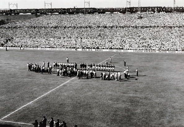 Sport Football. World Cup Finals. July 1954. Germany v Hungary. Both teams line-up at the start of the match. Above the crowded stand a railway train passes.