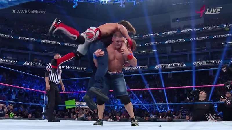 John Cena lifts two men onto his shoulders for the Attitude Adjustment.