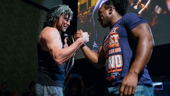 Xavier Woods and Kenny Omega shake hands before their video game showdown.