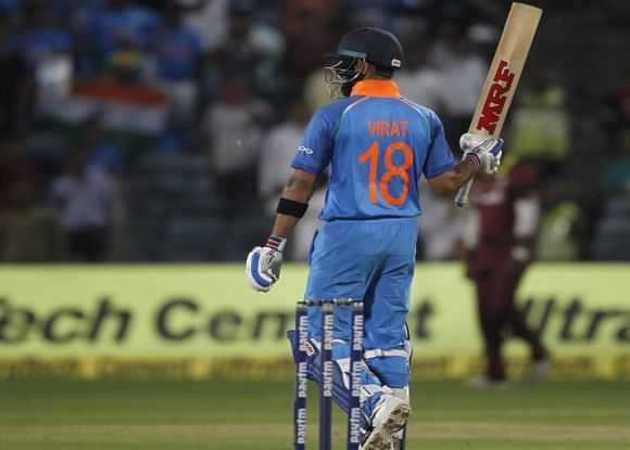 Kohli raises his bat after reaching the three-figure mark