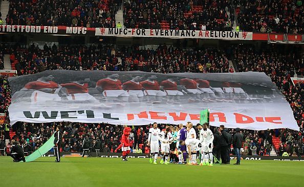 The Stretford End holding up a tifo of the Busby Babes