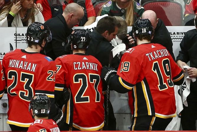 Flames coach Bill Peters hit in face by puck