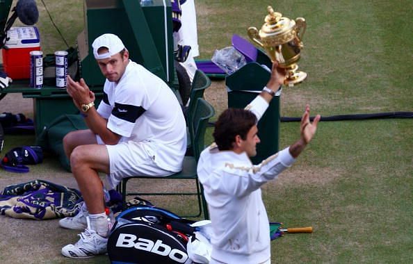 A dejected Roddick looks on as Roger Federer celebrates his 6th Wimbledon Championships win