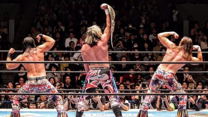 Kenny Omega poses in ring with the Young Bucks.