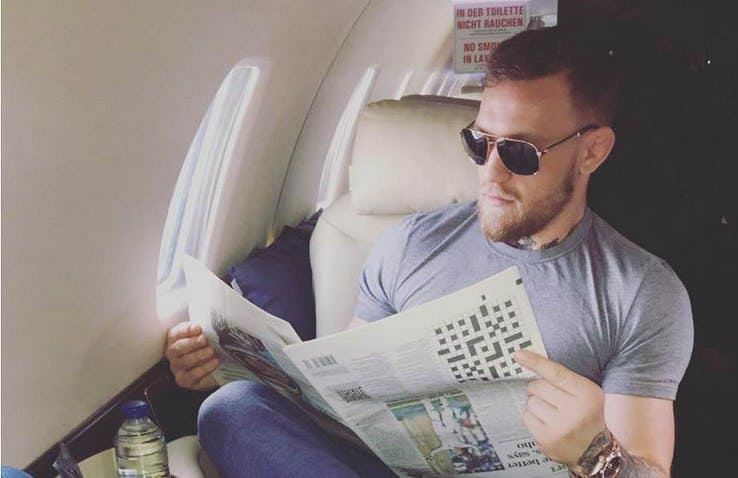 Conor McGregor posing with an upside-down newspaper