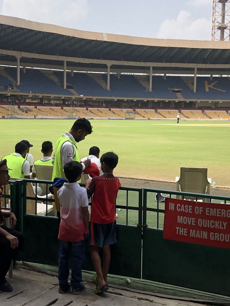 Two enthusiastic kids taking an autograph from the Karnataka players as the security looks on