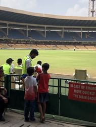 Two enthusiastic kids taking an autograph from the Karnataka players as the security looks on