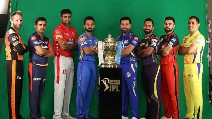 8 franchise captains of the IPL stand in with the IPL trophy in the middle.