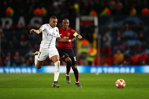 Ashley Young and Kylian Mbappe chase the ball