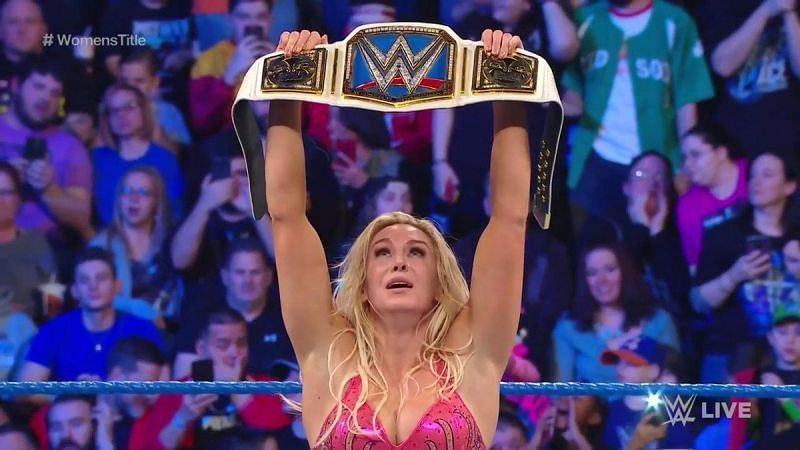 Charlotte Flair hefts the WWE Smackdown Women's title overhead