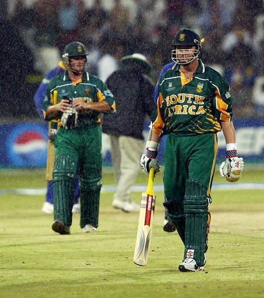 Lance Klusener and team-mate Mark Boucher of South Africa leave the field as rain falls