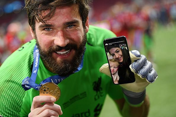 Alisson celebrates with his Champions League winners medal and a video call with family