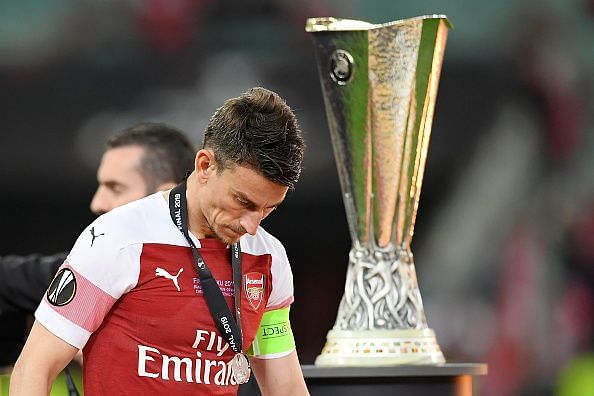 Koscielny walks past the Europa League trophy after Chelsea&#039;s 4-1 win over the Gunners late last month