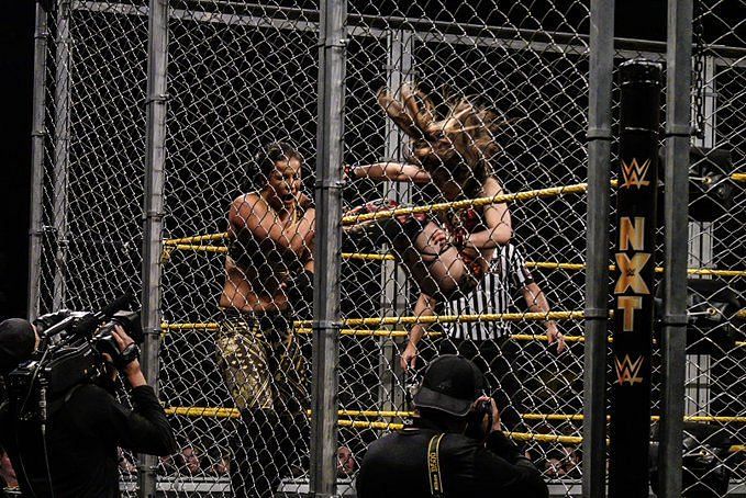 Shayna Baszler sandwiched between Io Shirai and the unforgiving steel cage