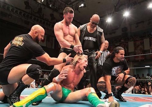 The Bullet Club pose with Kenny Omega&#039;s prone body