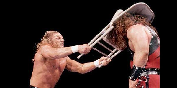 Triple H blasts a masked Kane with a steel chair
