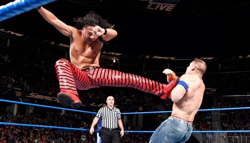 Shinsuke Nakamura unloads a rolling sole butt on John Cena.