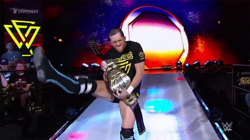 Kyle O&#039;Reilly striking his signature air guitar pose with the NXT Tag Team title