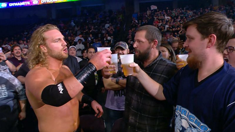Hangman Adam Page enjoys a cold one with some AEW fans at ringside.