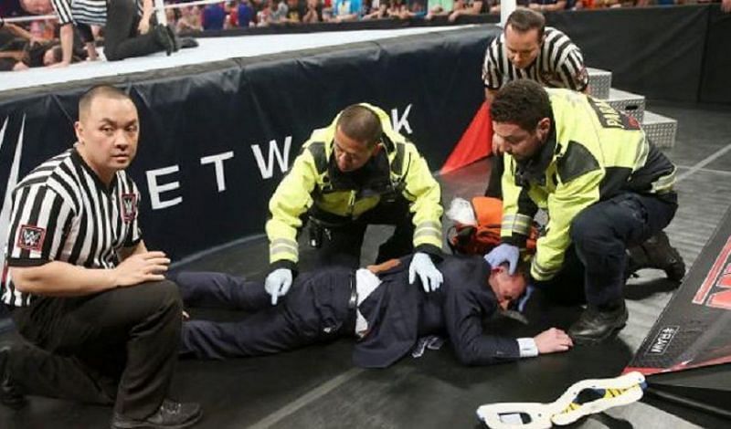 Michael Cole gets medical attention after being wiped out by Brock Lesnar