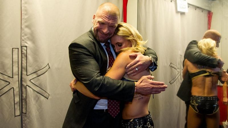 Charlotte Flair embraces with Triple H backstage.