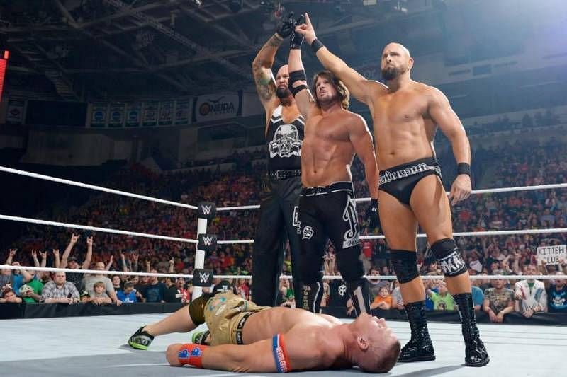 The OC (AJ Styles, Luke Gallows, and Karl Anderson) pose over a fallen John Cena in WWE
