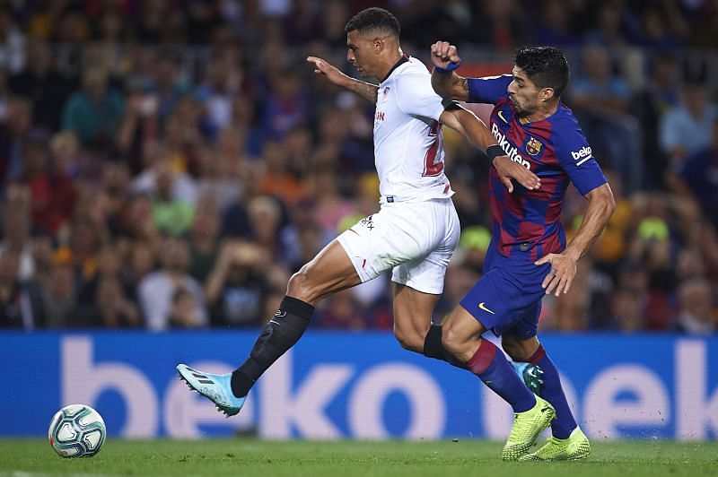 Diego Carlos of Sevilla FC (L) competes for the ball with Luis Suarez of FC Barcelona (R)