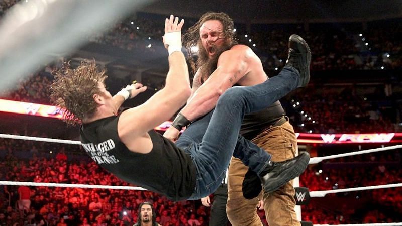 Brain Strowman beating up Dean Ambrose while Roman Reigns watches on