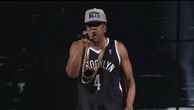 Jay-Z performing at an event wearing a Brooklyn Nets jersey