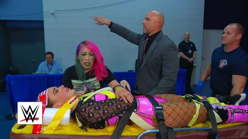 Asuka tends to Lana as she is being carried on a stretcher