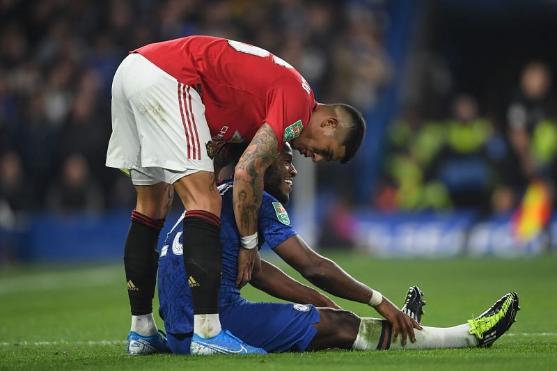 Michy Batshuayi of Chelsea is helped up by Marcos Rojo of Manchester United.