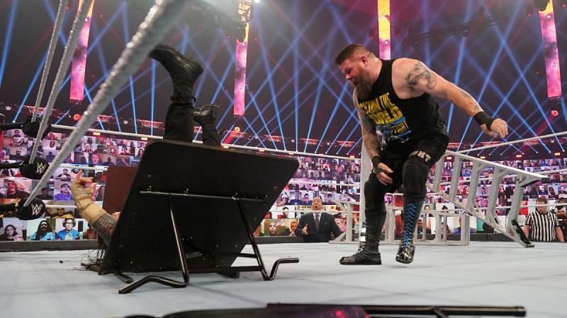 Kevin Owens drives Roman Reigns through a table in their WWE Championship match