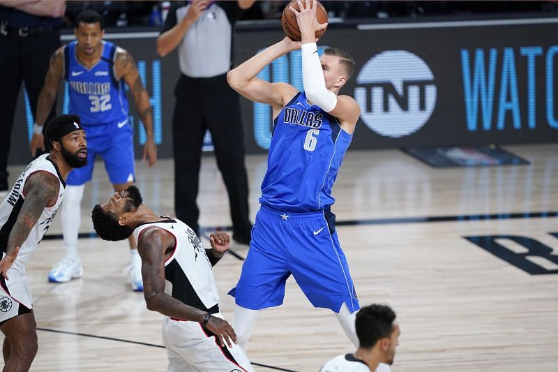 Paul George #13 of the LA Clippers falls back after colliding with Kristaps Porzingis #6 of the Dallas Mavericks.