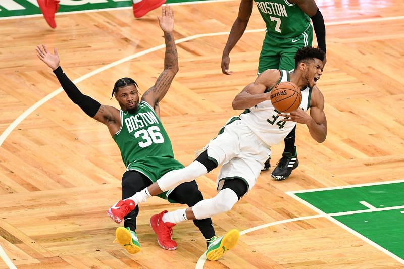 Giannis Antetokounmpo #34 of the Milwaukee Bucks trips over Marcus Smart #36 of the Boston Celtics.