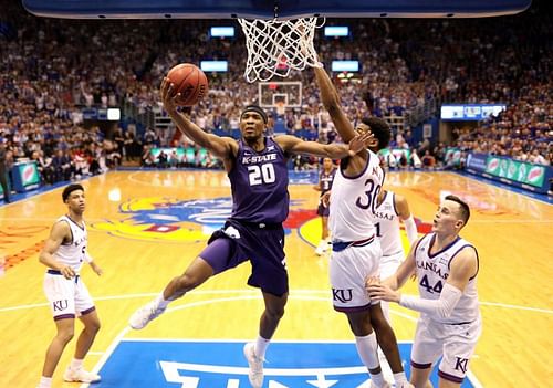 Xavier Sneed #20 of the Kansas State Wildcats drives toward the basket as Ochai Agbaji #30 of the Kansas Jayhawks