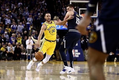 Stephen Curry dribbles past Nikola Jokic.