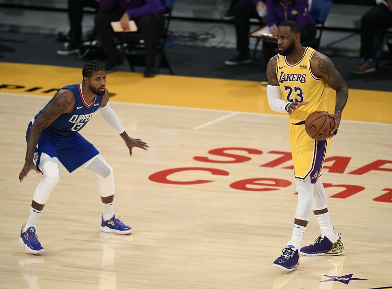 LeBron James #23 of the Los Angeles Lakers controls the ball as he is guarded by Paul George #13 of the LA Clippers.