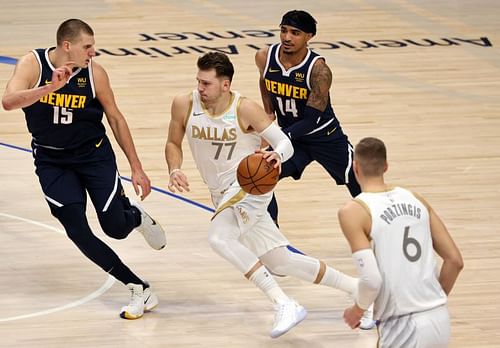 Luka Doncic #77 of the Dallas Mavericks dribbles the ball against Nikola Jokic #15 of the Denver Nuggets.