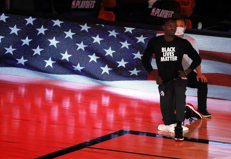 Chris Boucher #25 of the Toronto Raptors takes a knee during the national anthem before the start of a game against the Brooklyn Nets.
