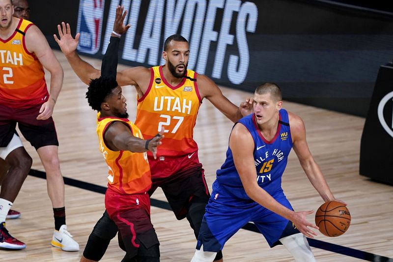Denver Nuggets&#039; Nikola Jokic looks to pass under pressure from Utah Jazz&#039;s Rudy Gobert and Donovan Mitchell during the first half of an NBA basketball first round playoff game 