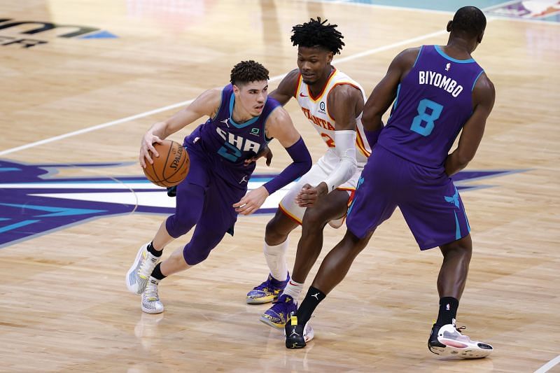 LaMelo Ball of the Charlotte Hornets drives to the basket against Cam Reddish.